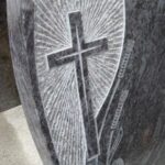 Nagrobni detajl s križem in rezbarijo v kamnu.