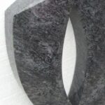 Granitni nagrobni detajl na svetlejšem kamnitem ozadju.