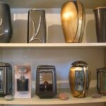 Različne bronaste vaze in nagrobne svetilke na polici.