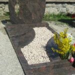 Sodoben nagrobni spomenik iz rdečkastega granita s steklenim križem